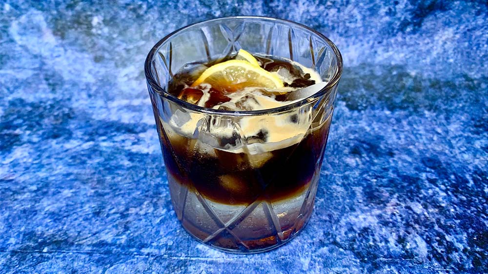 ľadová káva espresso tonik v sklenenom pohári na modrom štruktúrovanom podklade