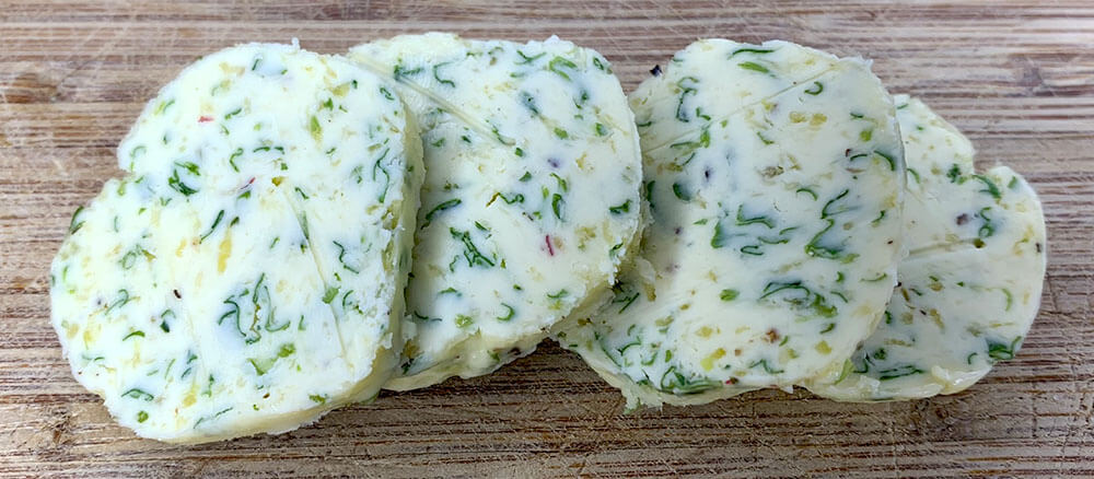 plátky bylinkového masla na derevenom podklade