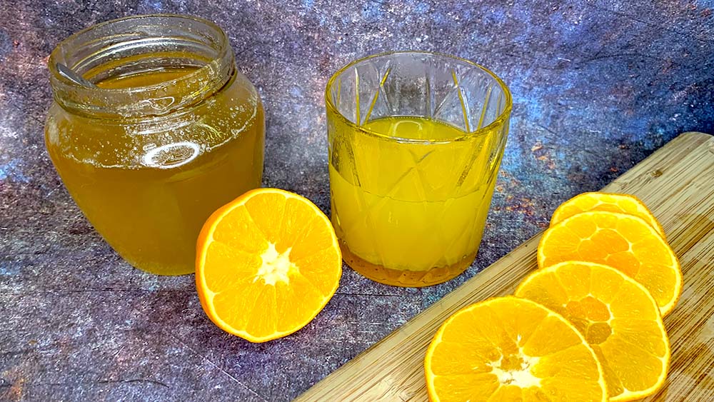 Citrusový nápoj v krištáľovom pohári s ingredienciami okolo na štruktúrovanom podklade