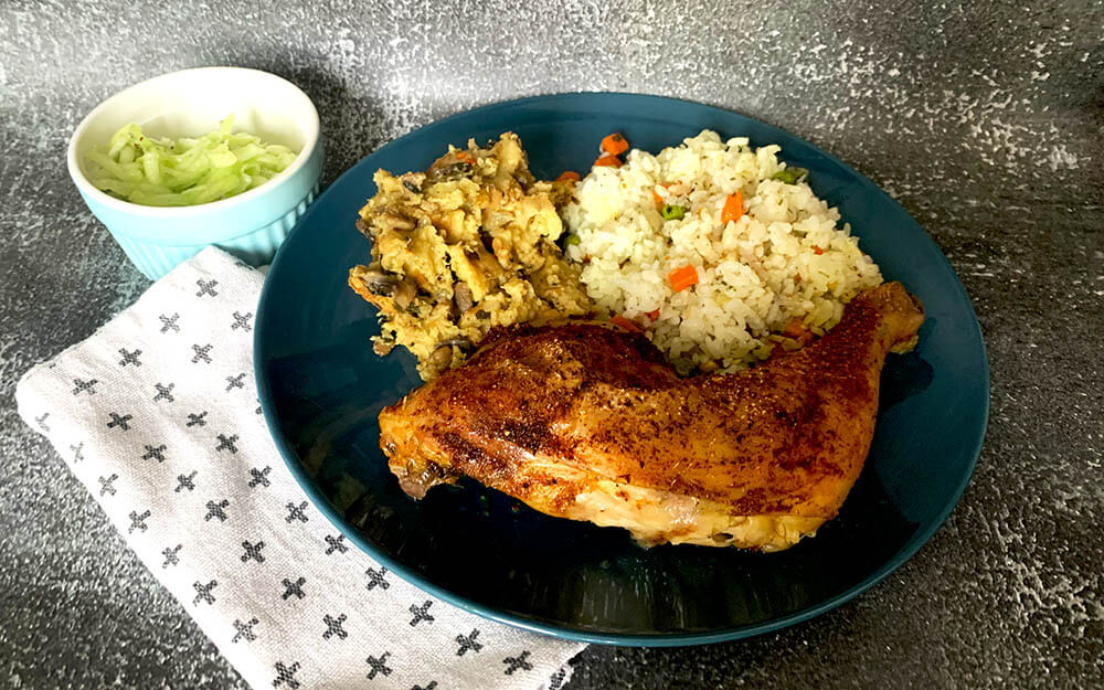 Hubová nádievka s pečeným kuracím stehnom, dusenou ryžou, servírované na modrom tanieri a uhorkovým šalátom